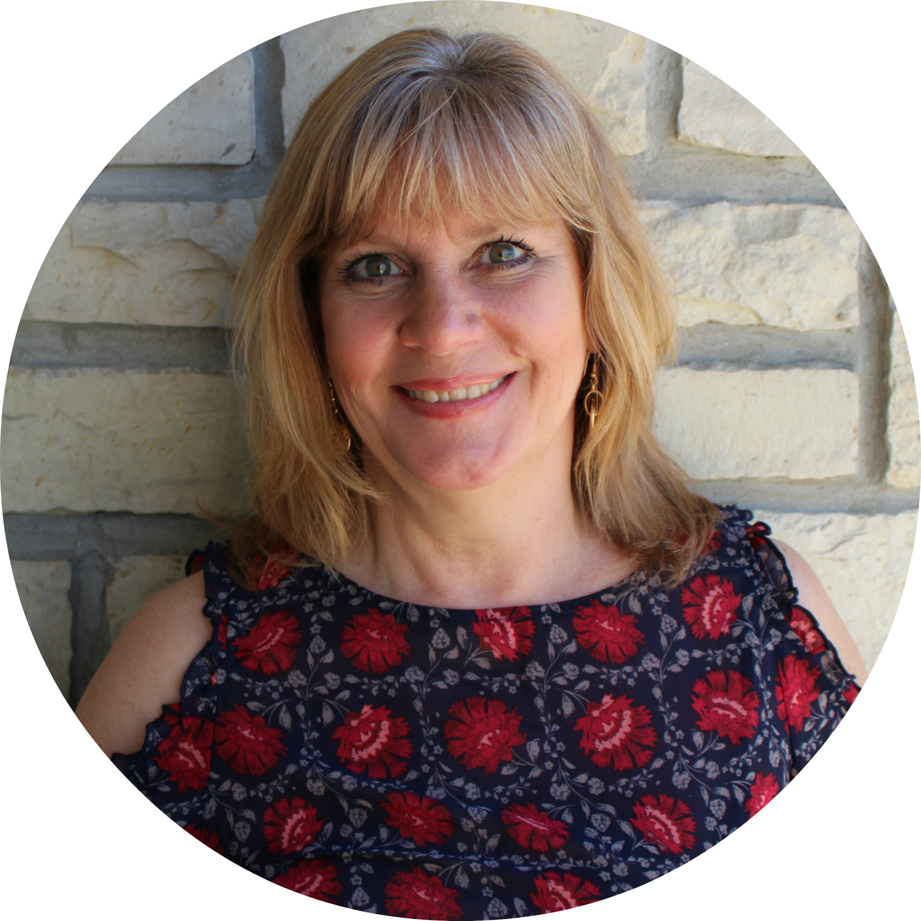 A woman is smiling in front of a brick wall