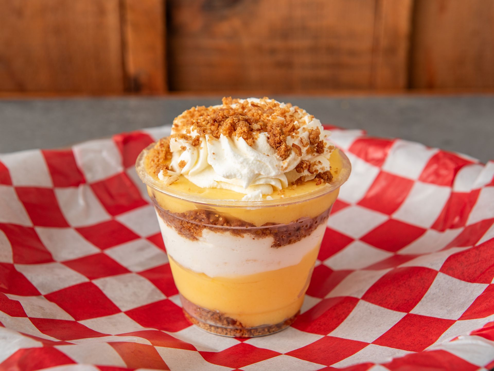 A banana pudding parfait on a red and white gingham parchment paper
