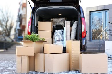 The back of a van is filled with cardboard boxes.