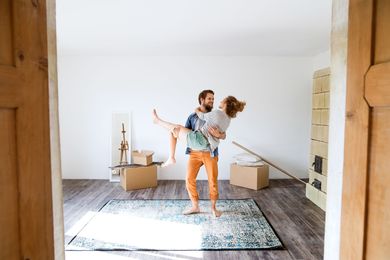 A man is carrying a woman in his arms in an empty room.