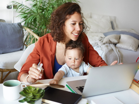 Single mom with baby in lap while working on laptop