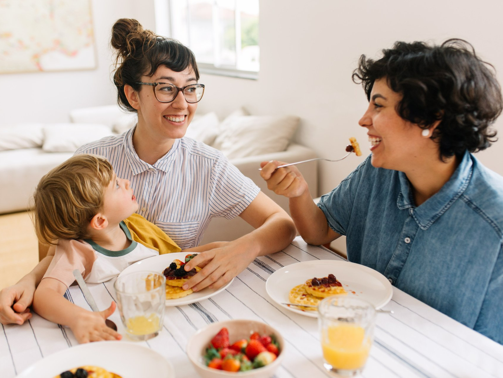 LGBT couple with child eating breakfast at kitchen table