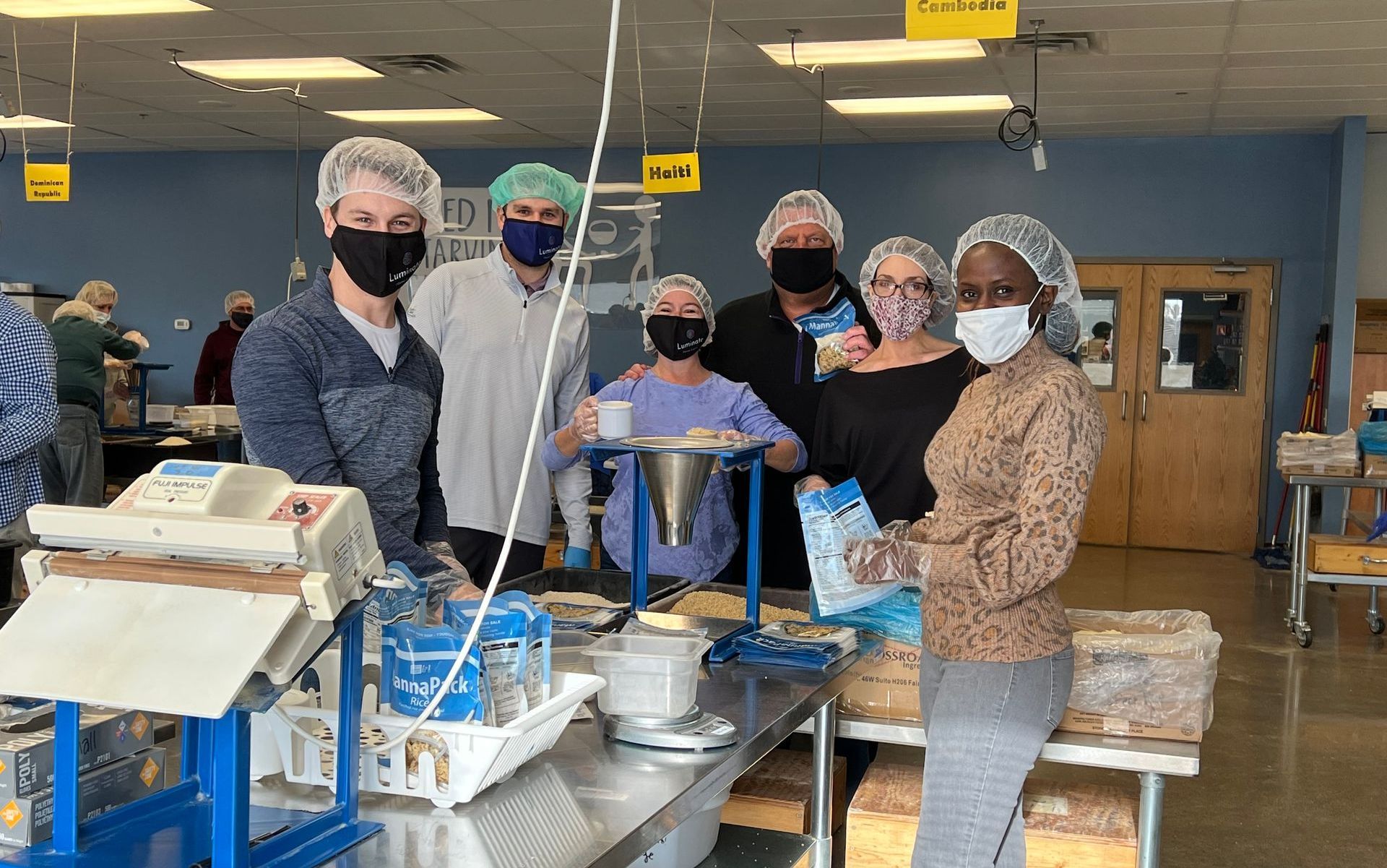 A group of people wearing masks and hair nets are standing in a room.