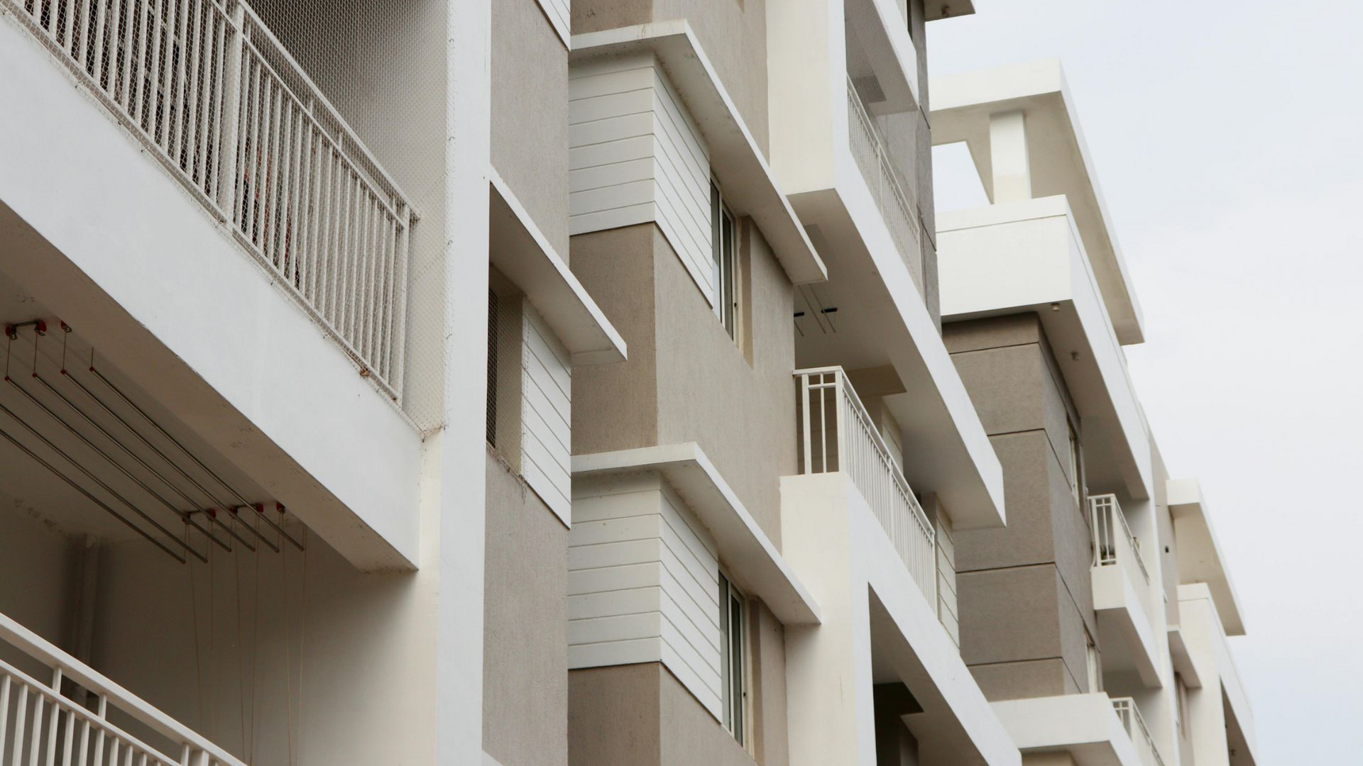 Multi-story apartment building with white and beige facade, balconies.