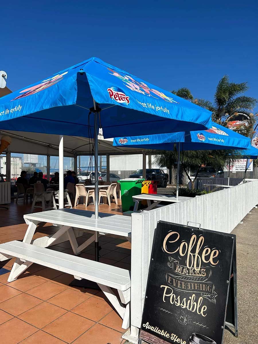 Picnic Table With Blue Umbrellas And A Signage — Mooloolaba Fisheries On The Spit In Mooloolaba, QLD