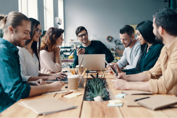 people sitting around a table looking at laptops