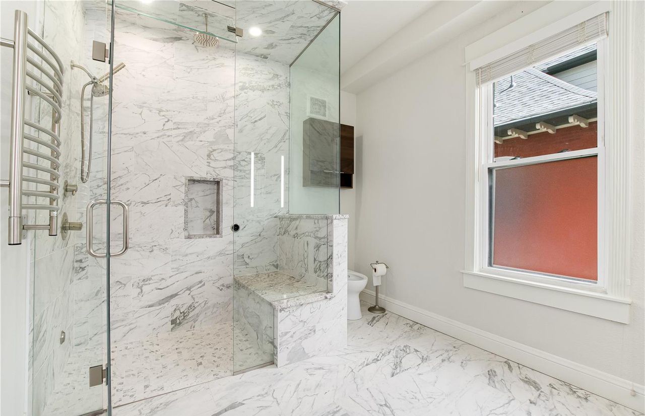A bathroom with a walk in shower and a window.