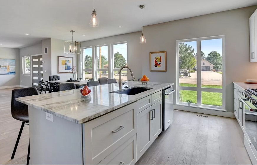 A kitchen with white cabinets and a large island in the middle.