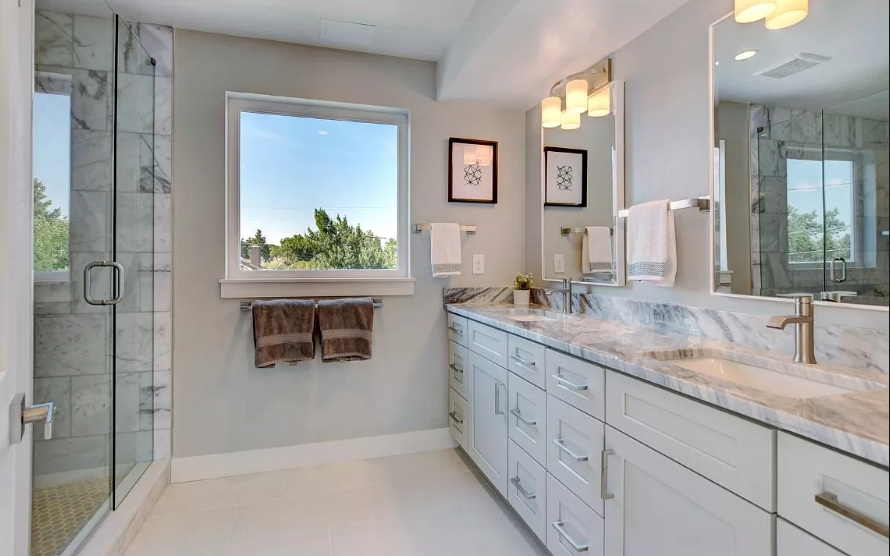 A bathroom with two sinks , a shower and a window.