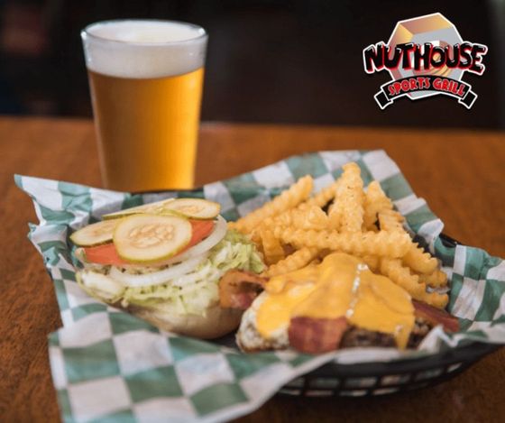 A hamburger and french fries in a basket next to a glass of beer