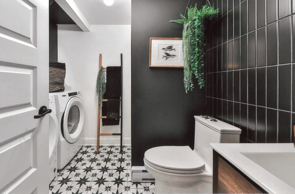 Salle de bains moderne avec lave-linge séchant, sol à motifs d'étoiles noires et blanches et mur d'accent noir avec carrelage métro.