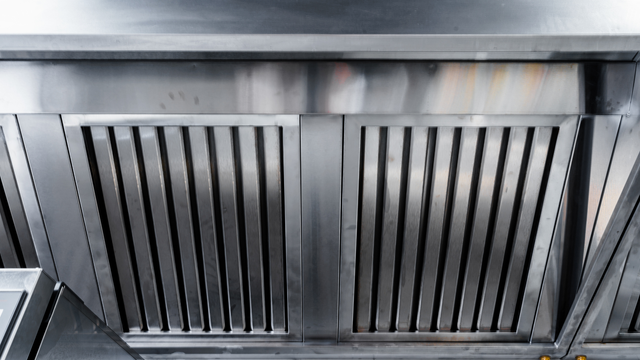 A close up of a stainless steel exhaust hood in a kitchen.