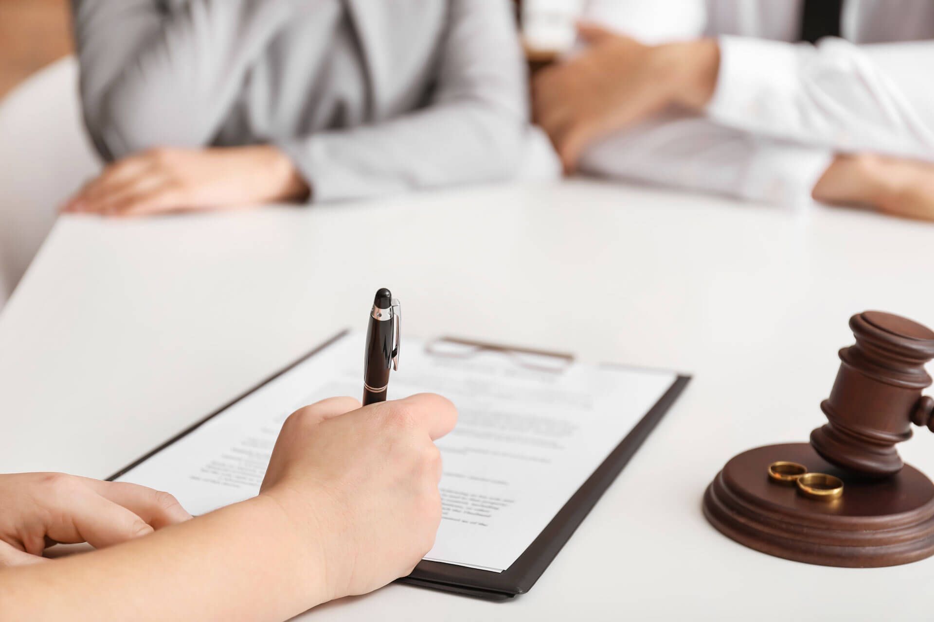 A woman is writing on a clipboard next to a judge's gavel.