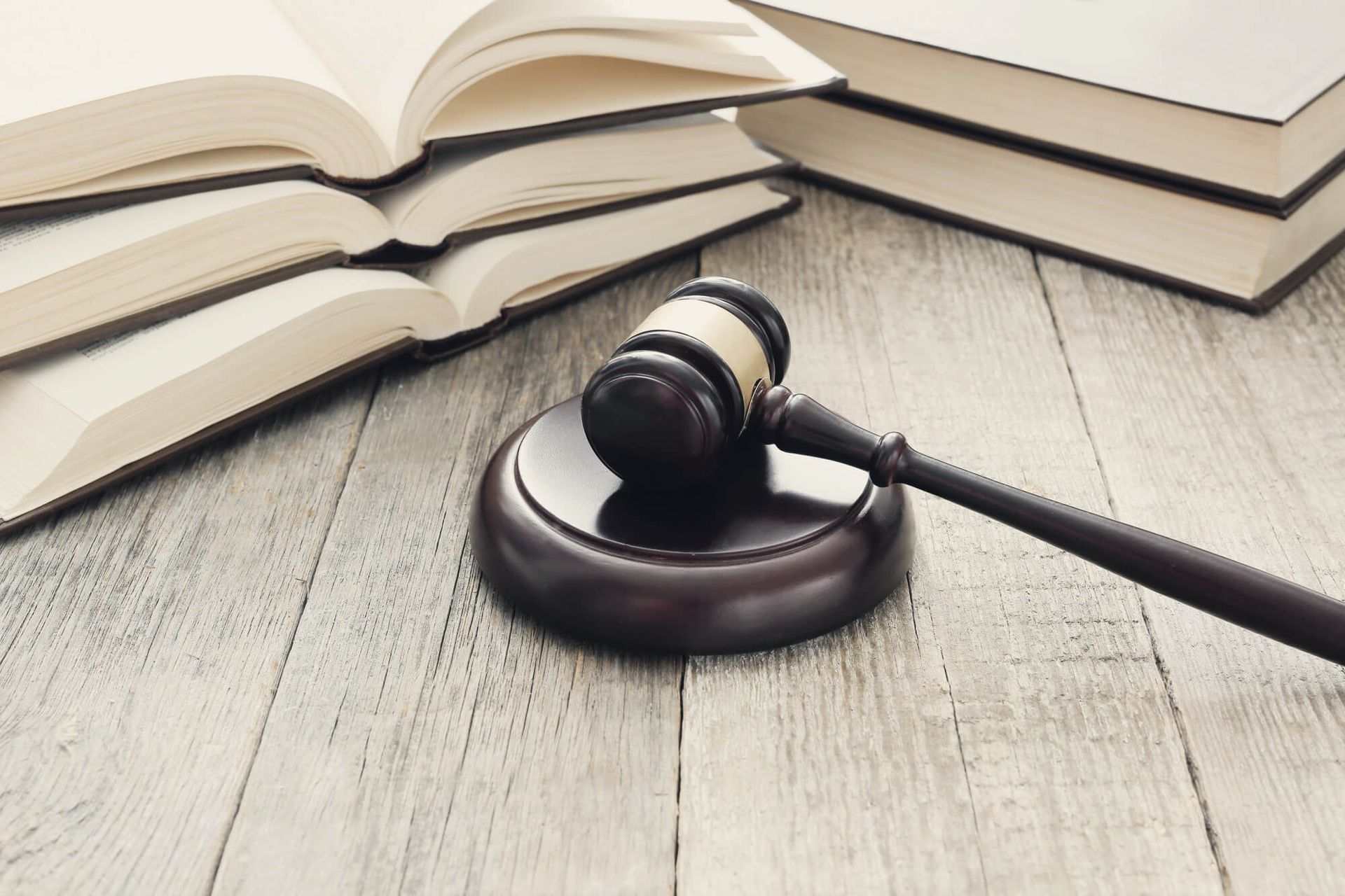 A judge's gavel is sitting on a wooden table next to a stack of books.