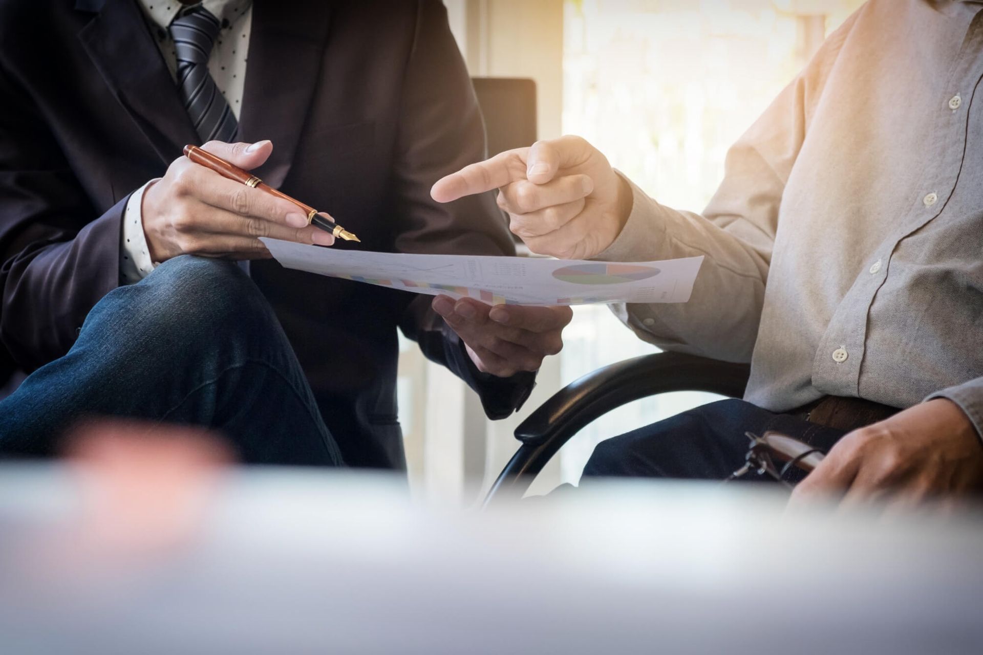 Two men are sitting at a table looking at a piece of paper.