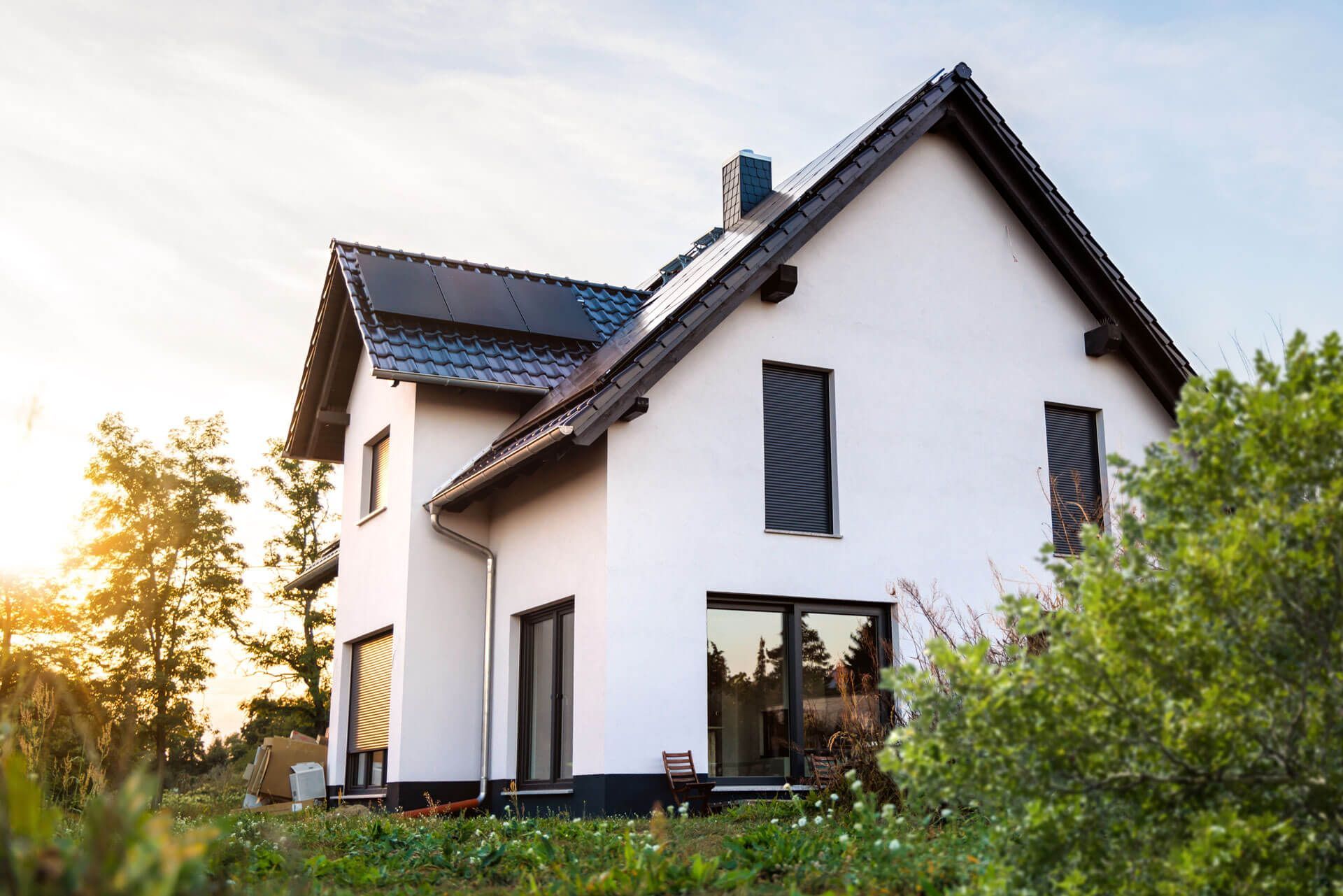 A white house with black trim and solar panels on the roof.