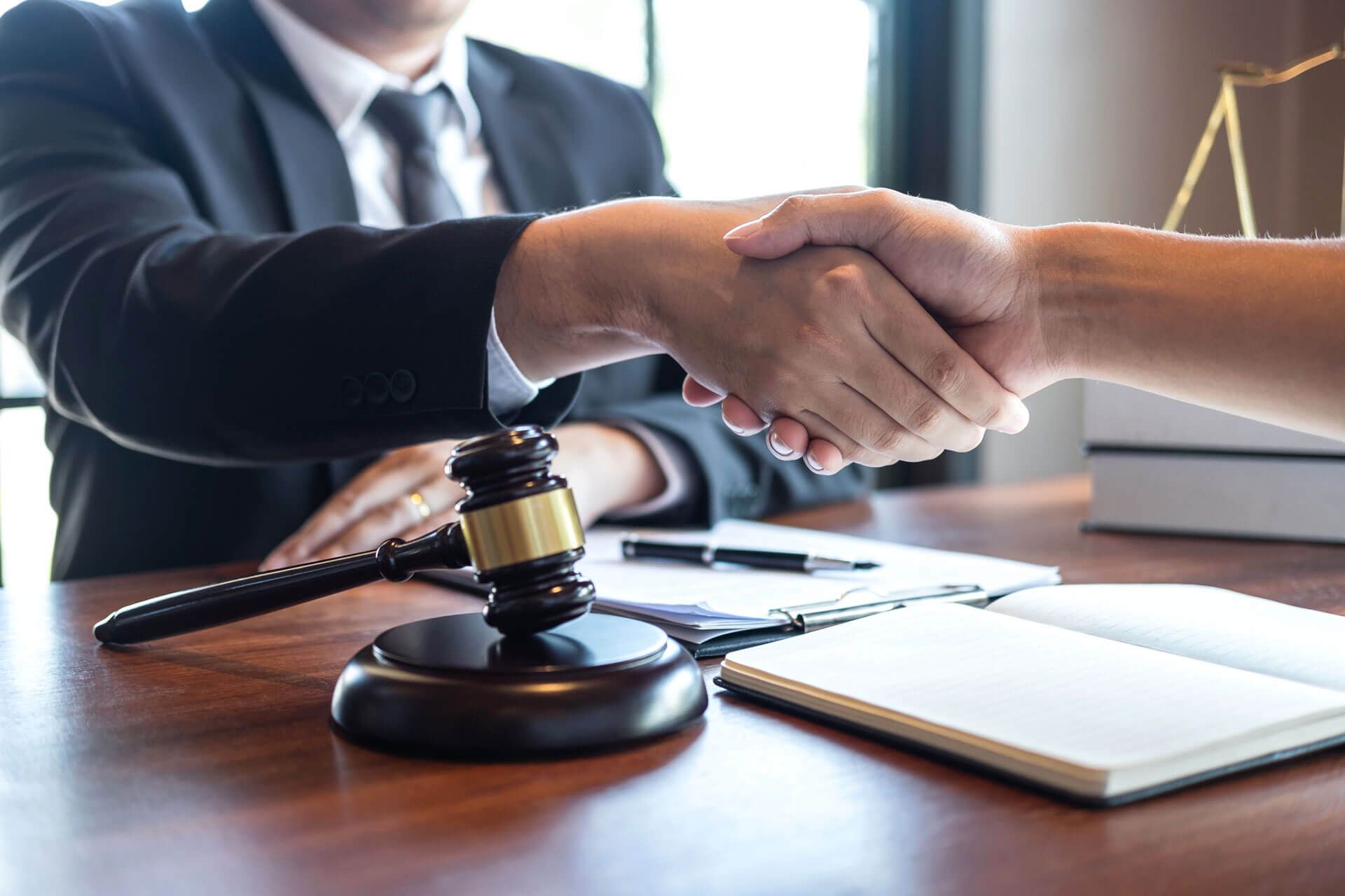 A judge is shaking hands with a client in front of a gavel.