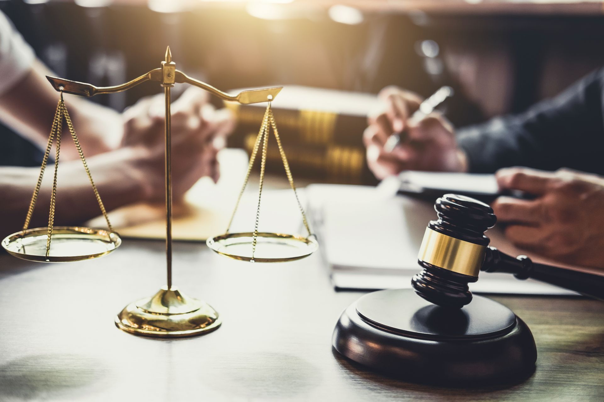 A group of people are sitting at a table with scales of justice and a judge's gavel.