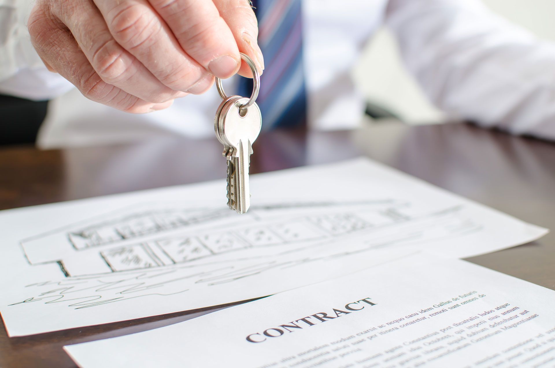 A man is holding a key over a contract.