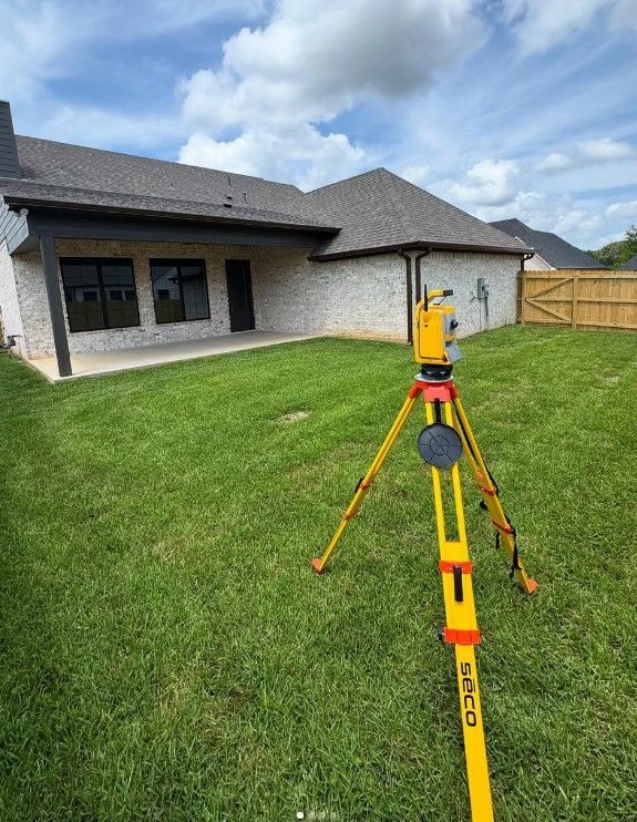 A yellow tripod is sitting in the grass in front of a house.