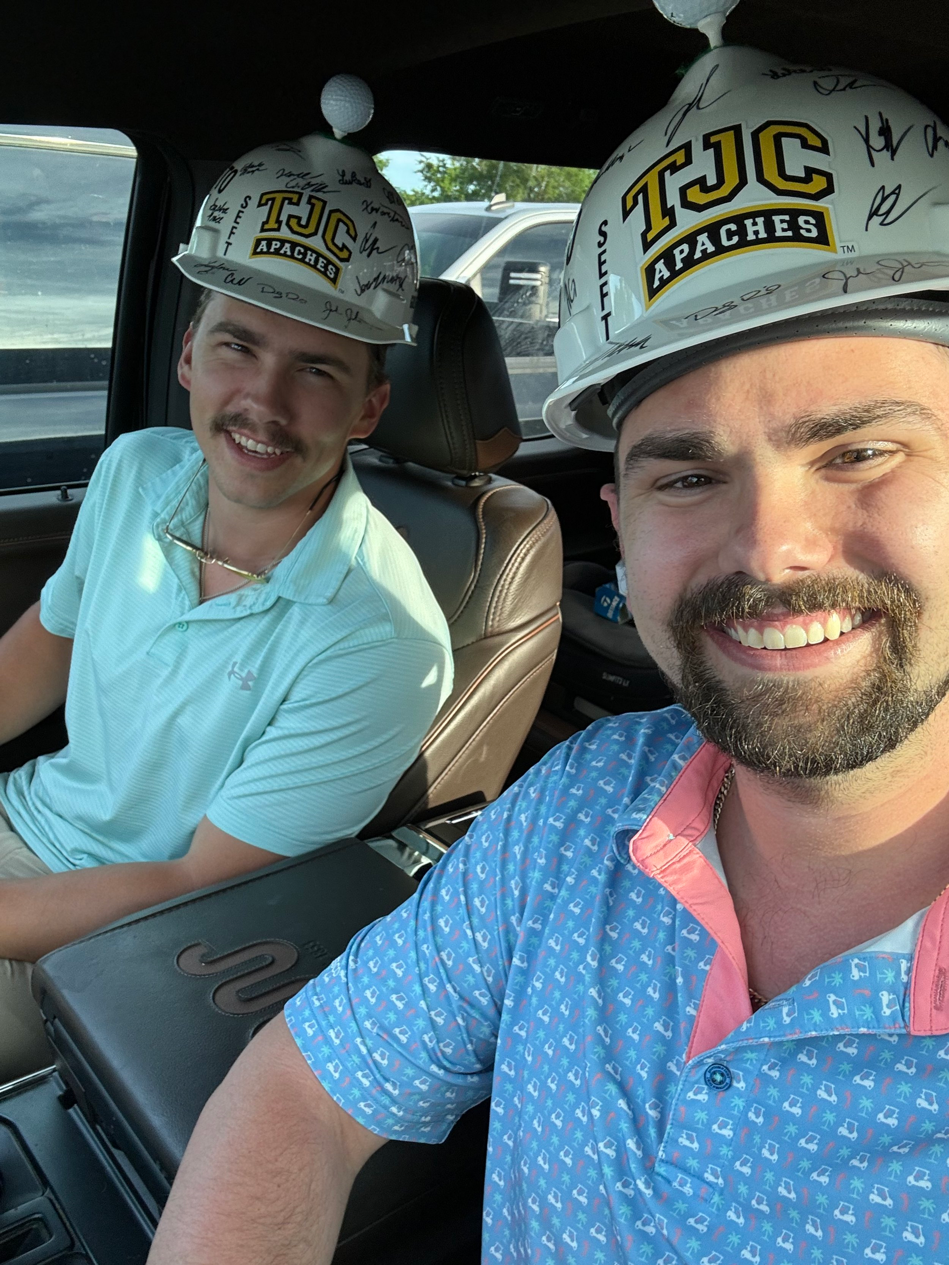Two men wearing hard hats are sitting in a car.