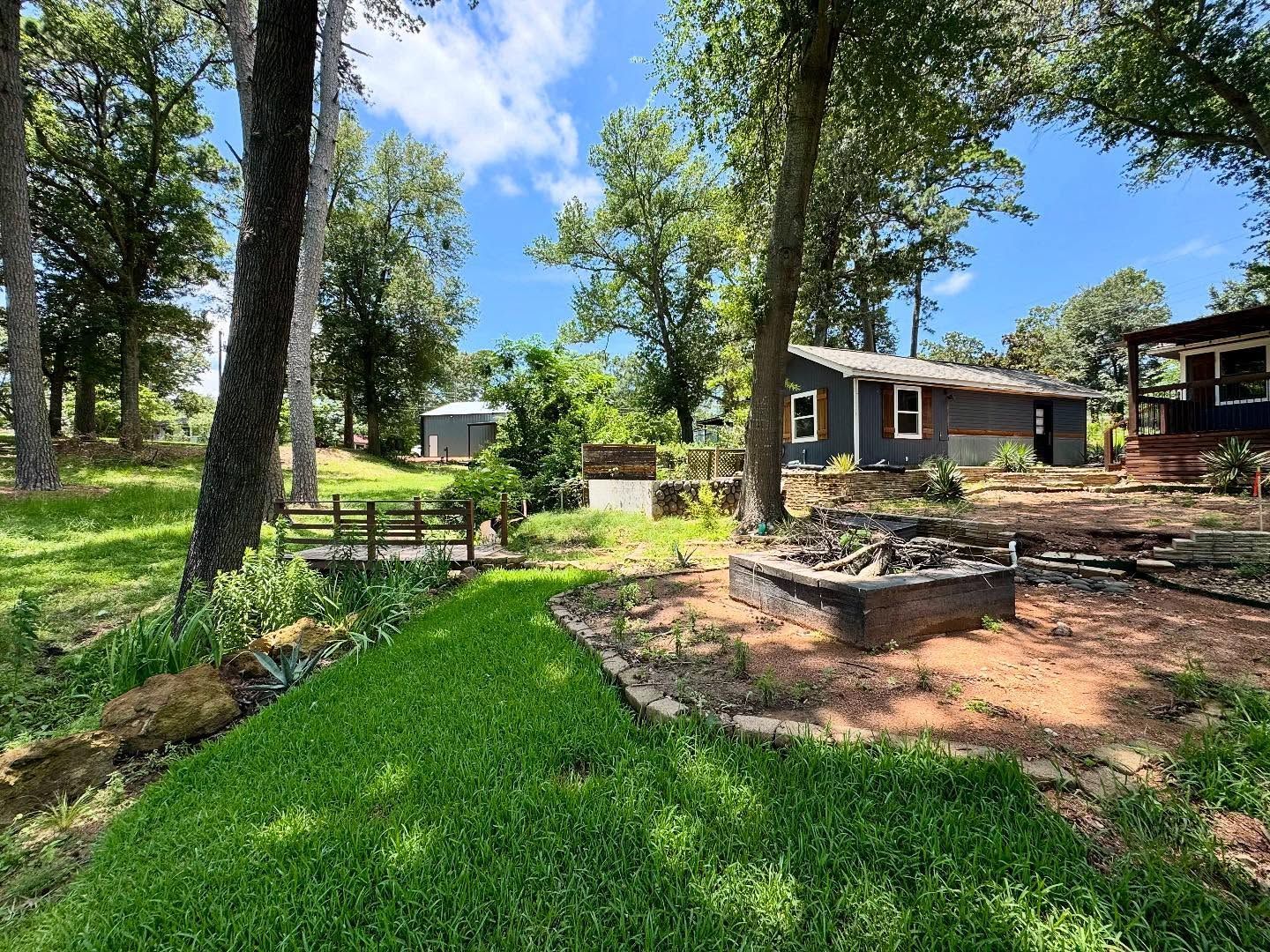 A house is sitting in the middle of a lush green field surrounded by trees.