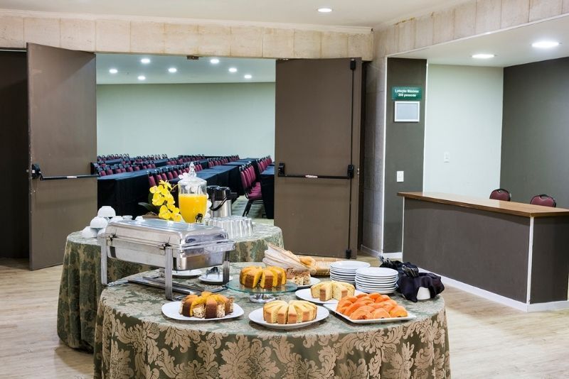 Mesa de buffet do hotel com café, doces e frutas no saguão de conferências.
