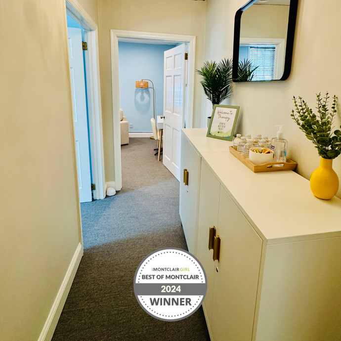 Hallway with a white cabinet, mirror, and doors. Award winner logo on the floor.