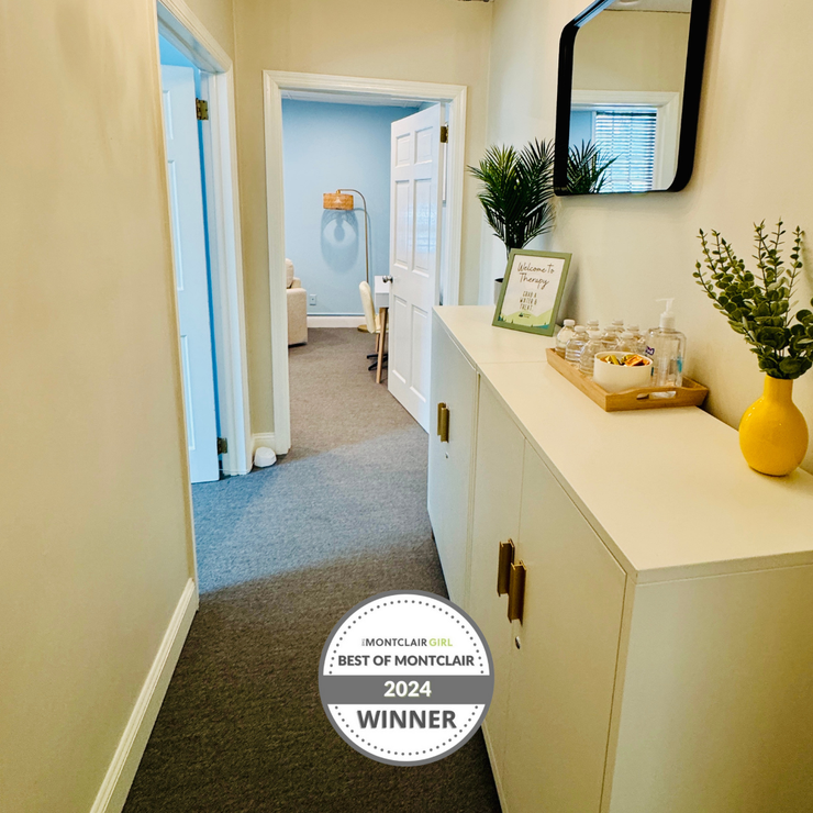 Hallway with a white cabinet, mirror, and doors. Award winner logo on the floor.