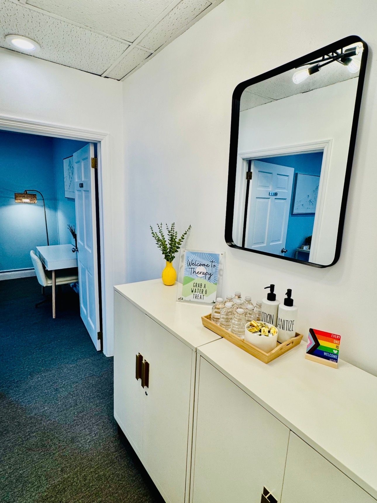 White cabinet with mirror and open doorway to office.