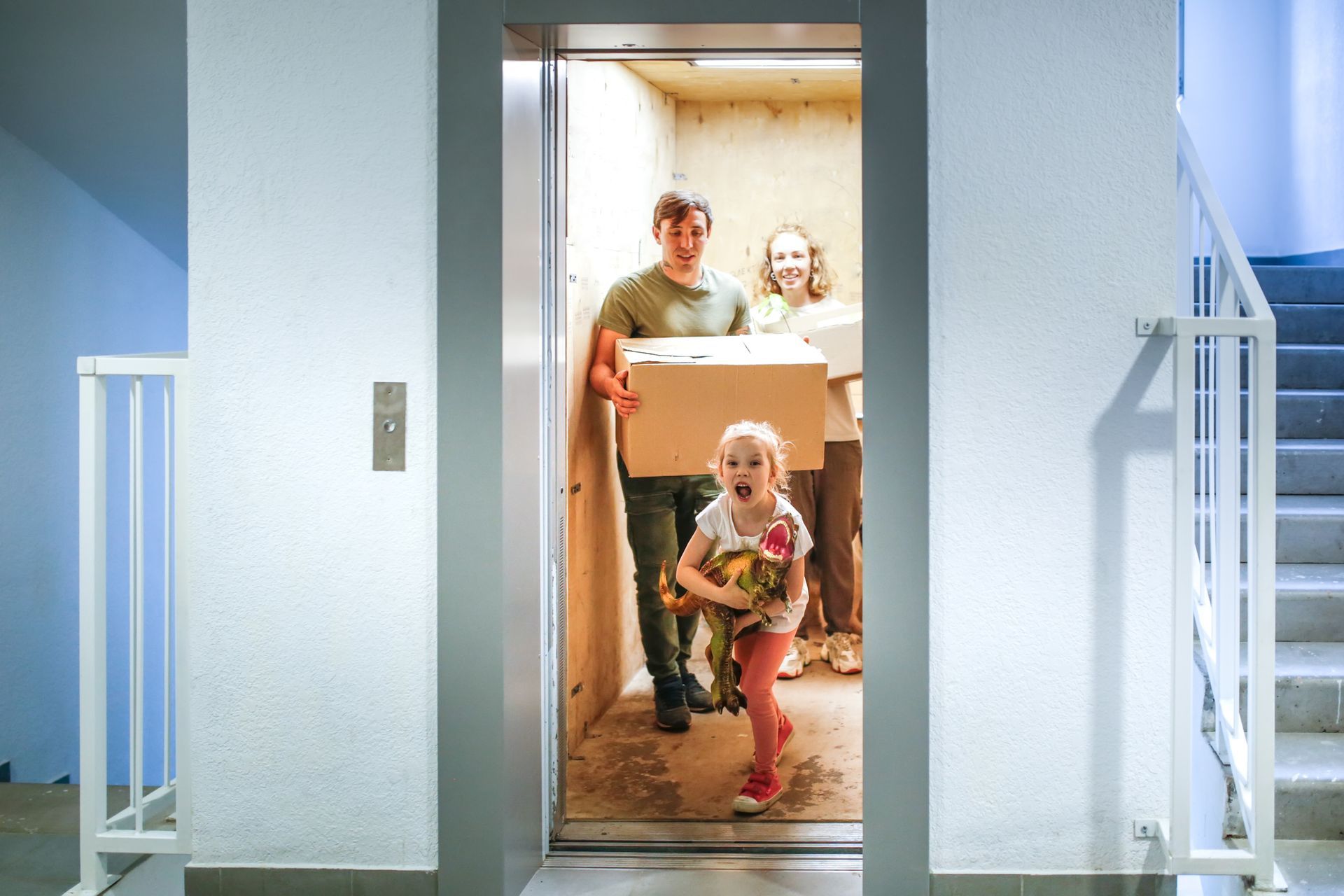 Un uomo e una bambina trasportano delle scatole in un ascensore.