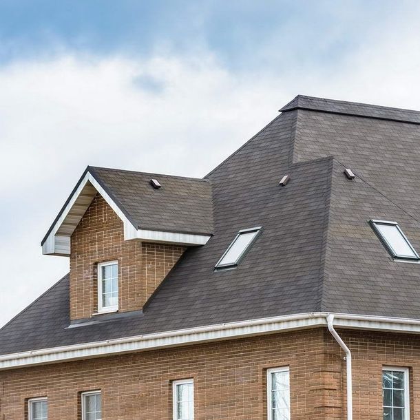 A brick house with a gray roof and two skylights