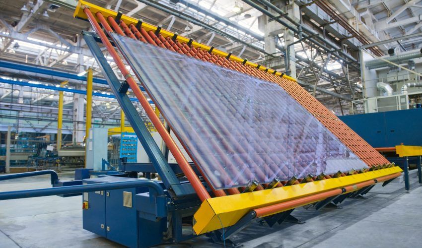 A large piece of glass is sitting on top of a machine in a factory.