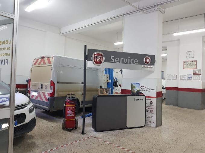 Area di accoglienza per l'assistenza auto con banco di servizio, furgone e estintore rosso sotto luminose luci fluorescenti.