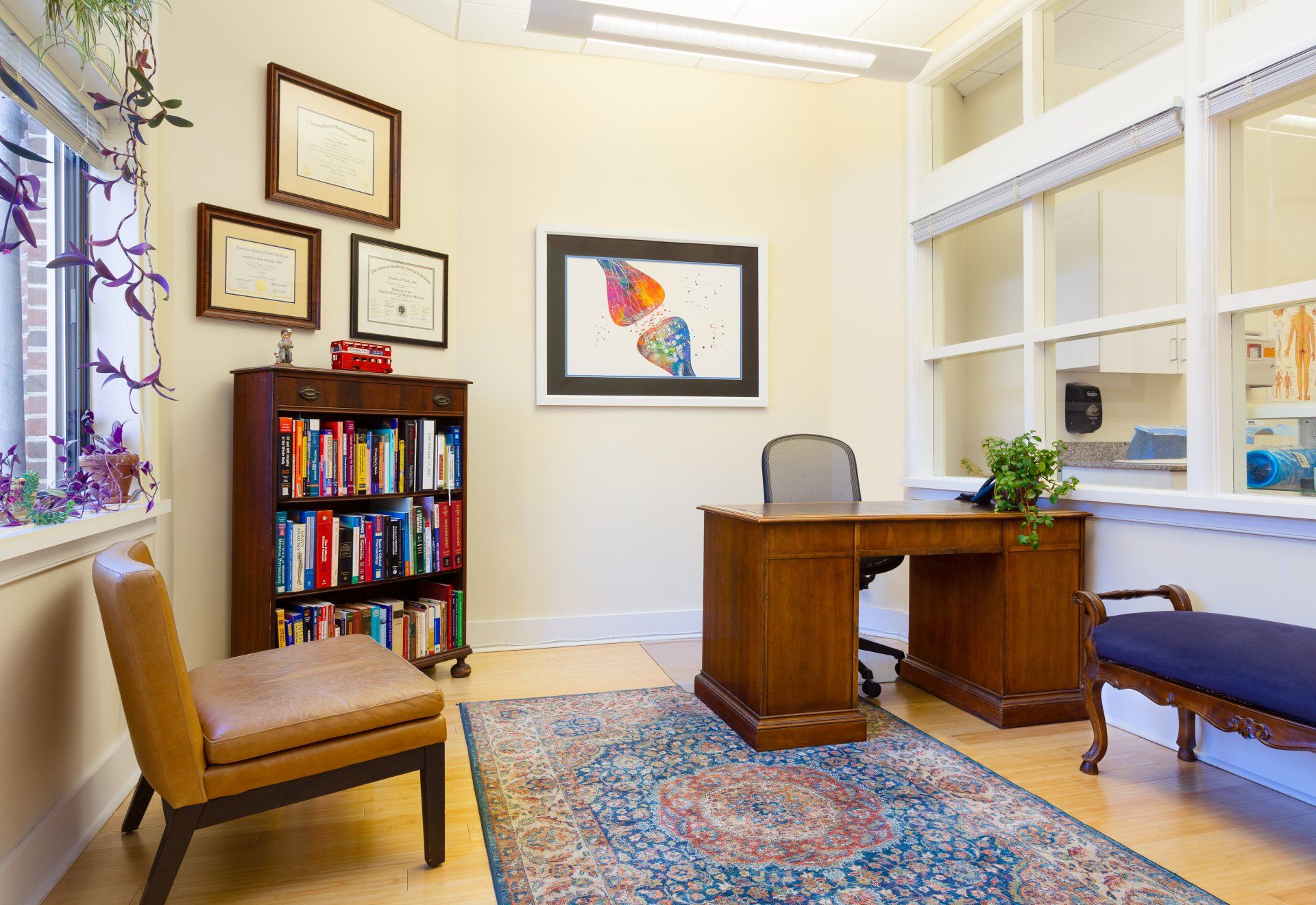 A room with a desk , chair , bookshelf and rug.