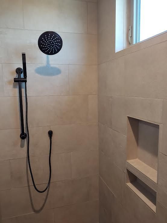 Two construction workers pouring cement into a rectangular form in front of a house.