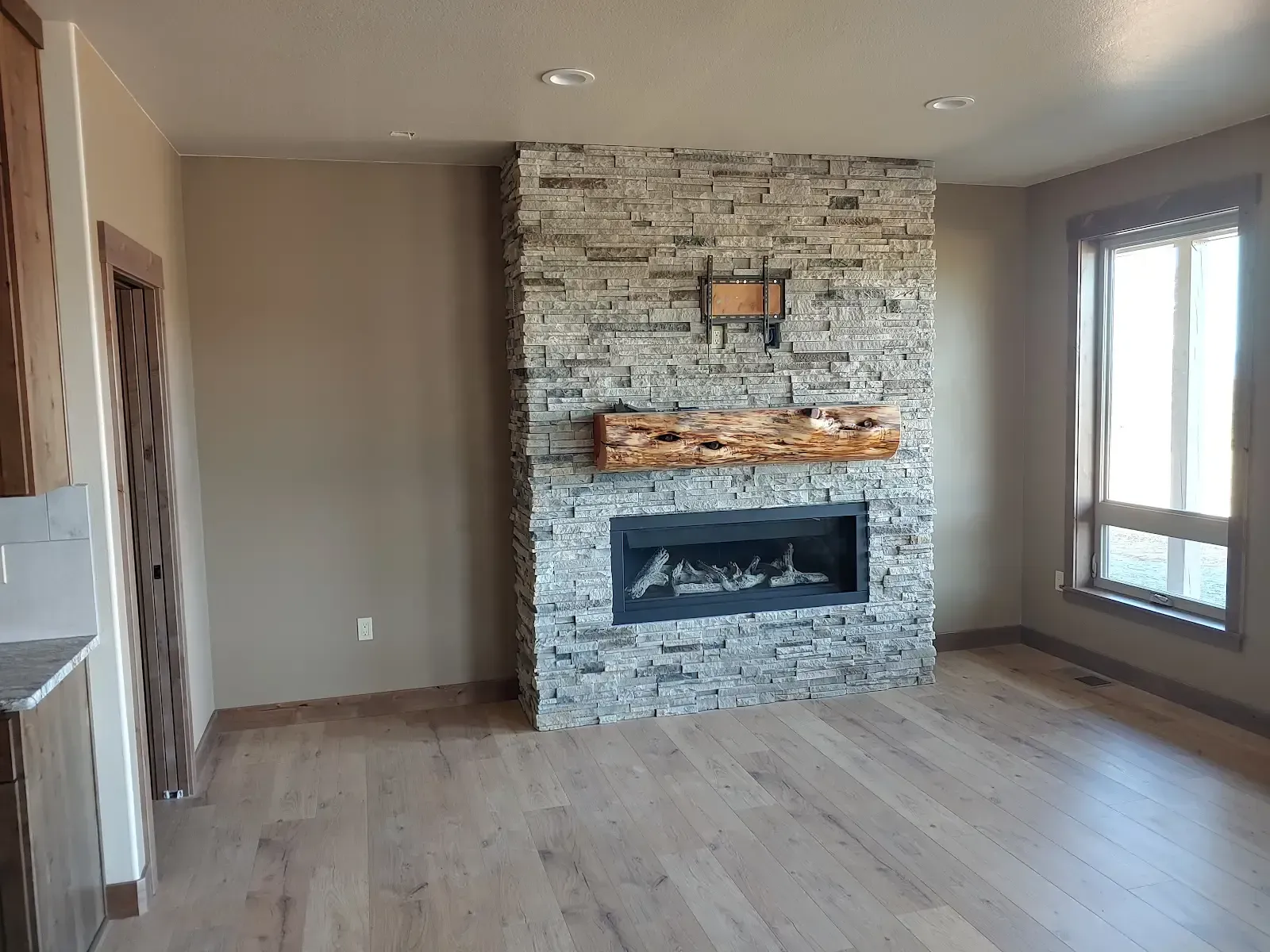 Construction site of a two-story house with an open garage. Workers are in the yard, and trees surround the property.
