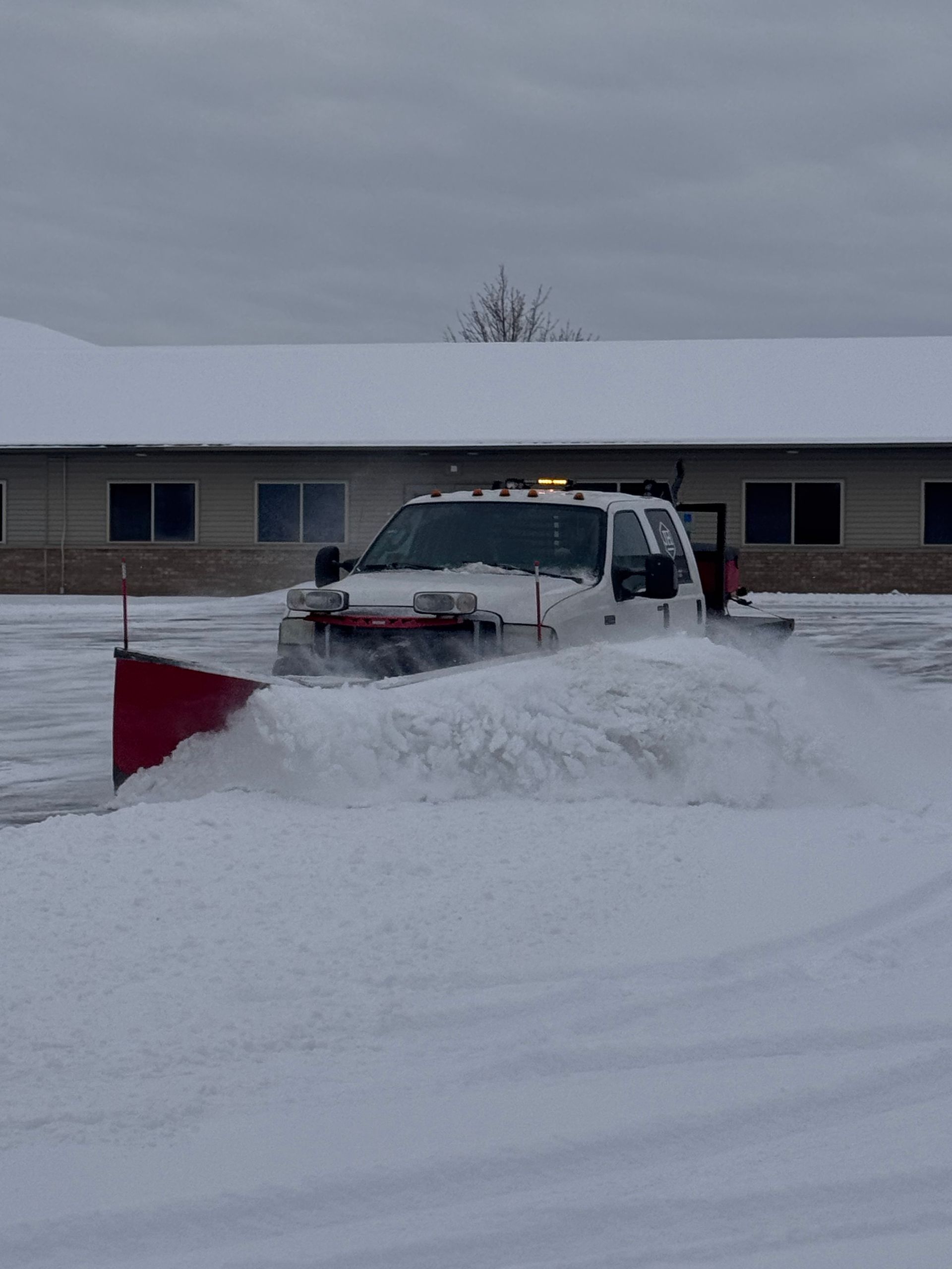 Snowplow clearing snow from a residential street in a snowstorm.