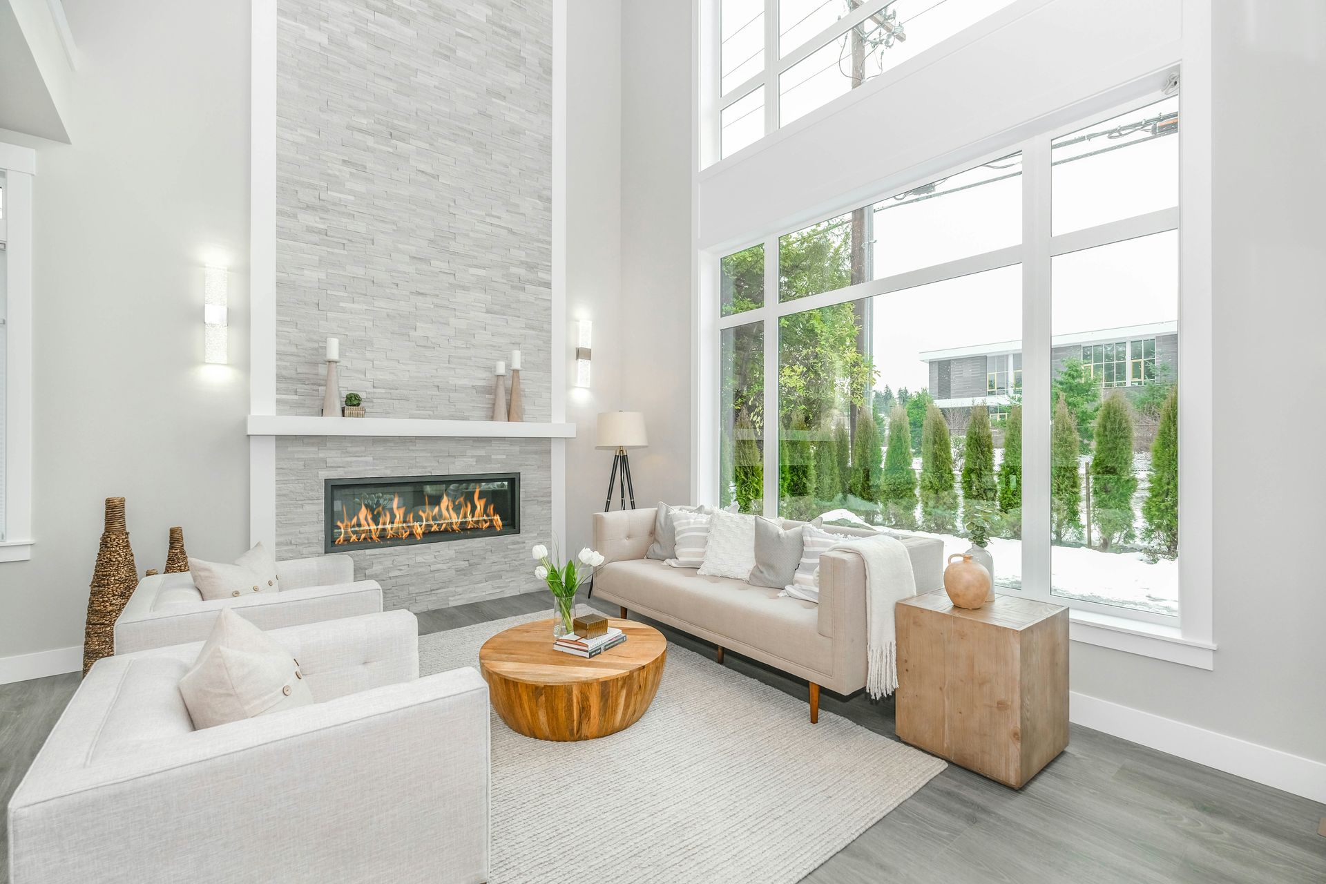 neutral living room with large fireplace and large windows.