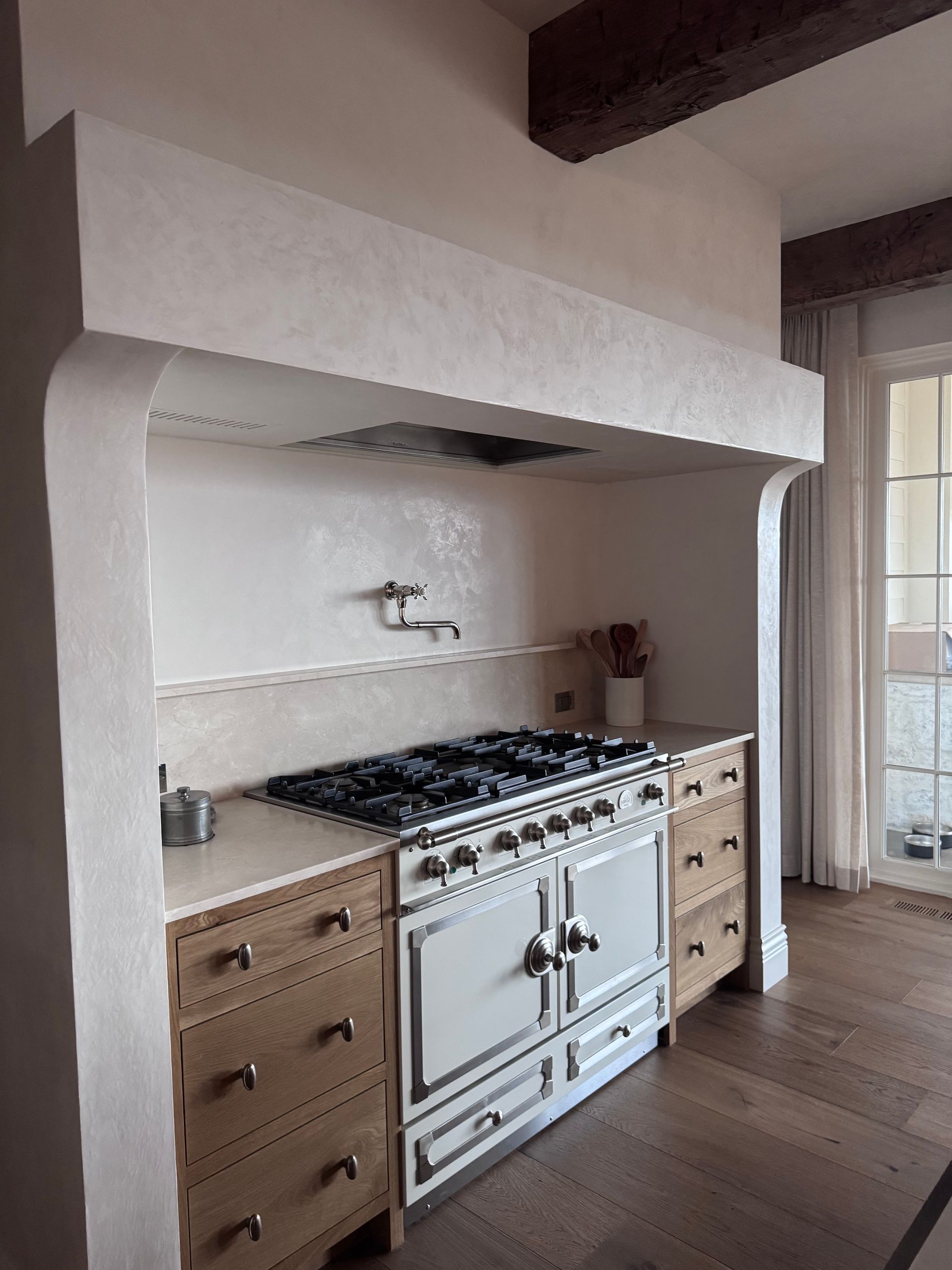 Kitchen range with white hood, white range, wood cabinets, and wood beams.