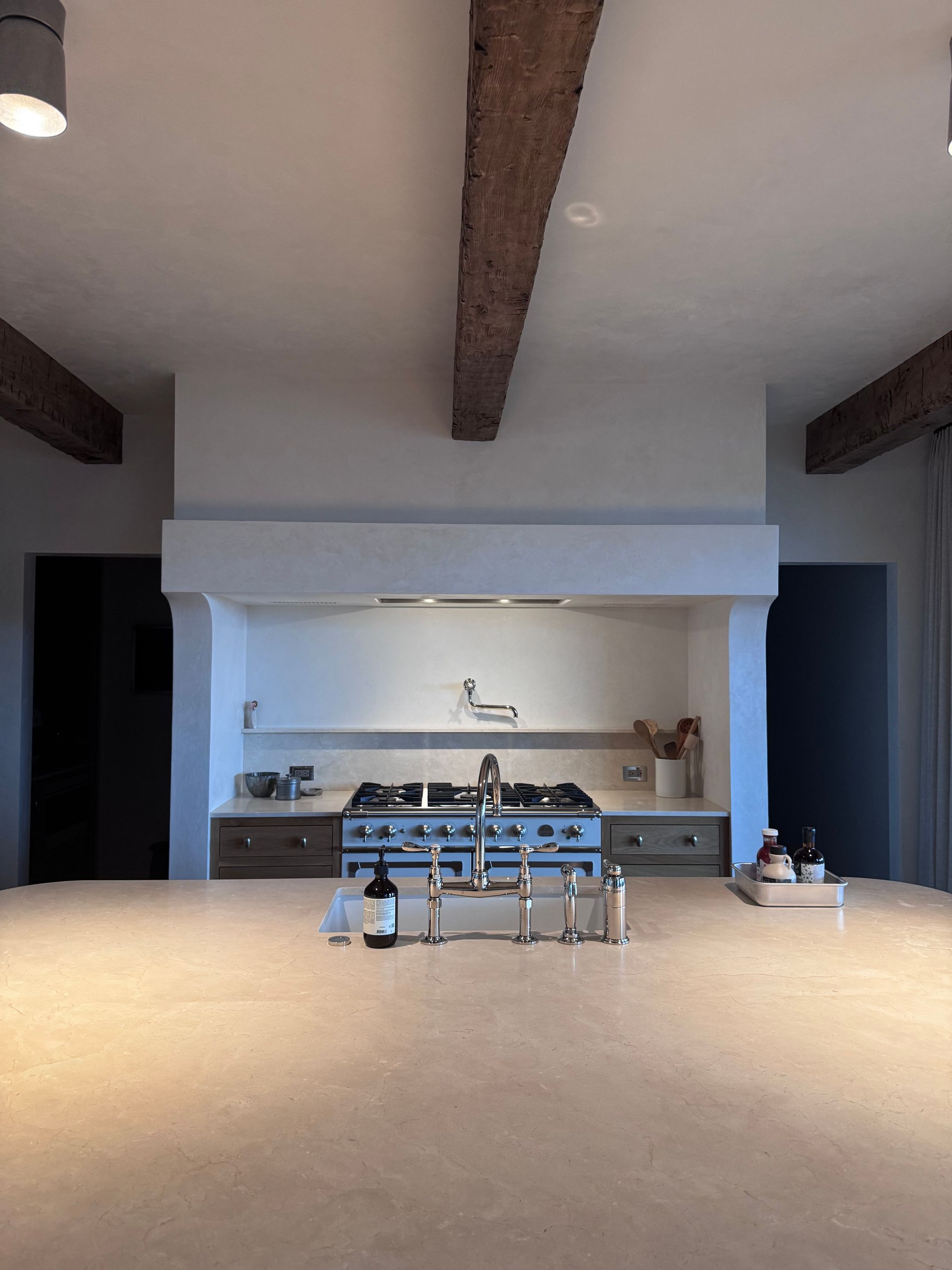 Modern kitchen with a stainless steel stove, island, and exposed beams.