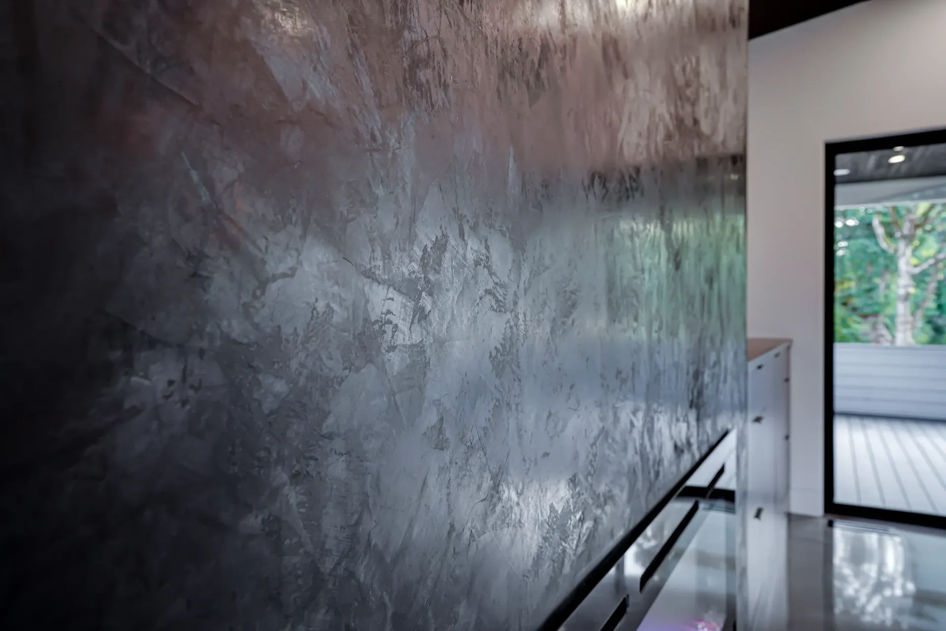 Textured, dark gray wall with metallic sheen; hallway with a door to an outside deck.