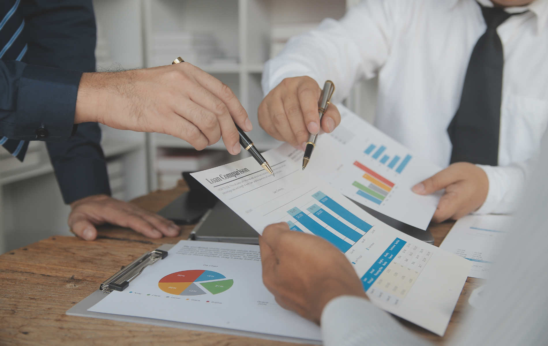 Businesspeople in meeting analyzing charts, graphs, and financial data.