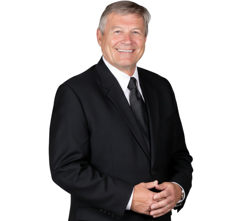 Man in a black suit smiles, arms crossed, set against a white backdrop.