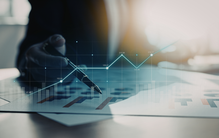 Person pointing at a financial graph with a pen, analyzing data and trends.