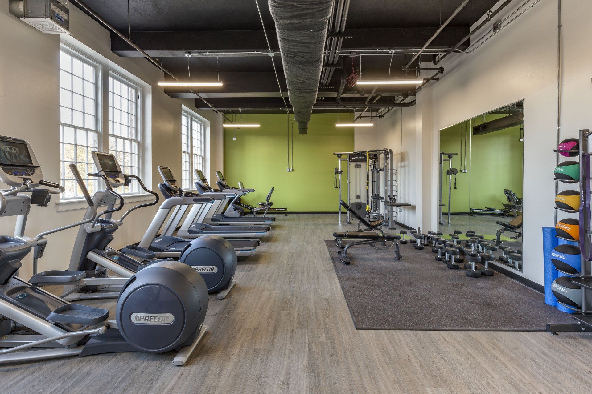 A large gym with a lot of equipment and a green wall.