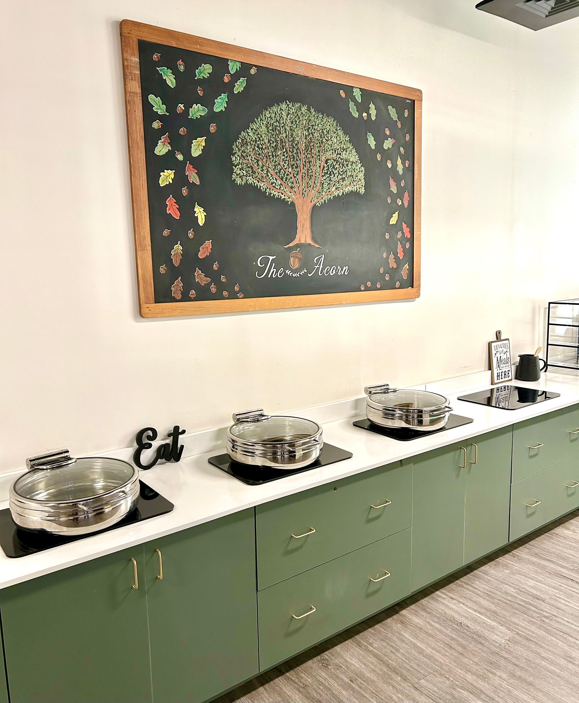 A kitchen with green cabinets and a chalkboard with a tree on it.