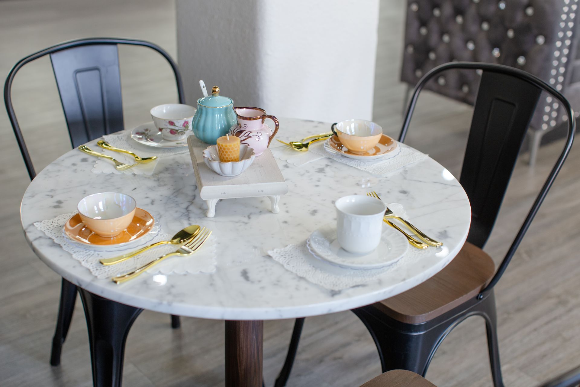 A round table with plates , cups , saucers , and spoons on it.