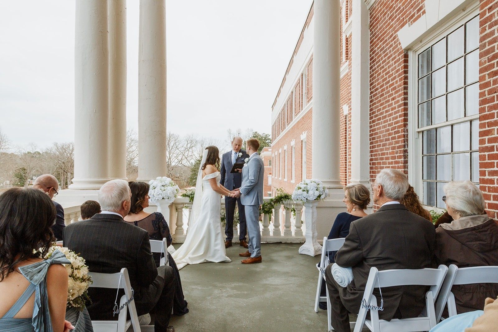 A bride and groom are sitting on a swing holding hands.