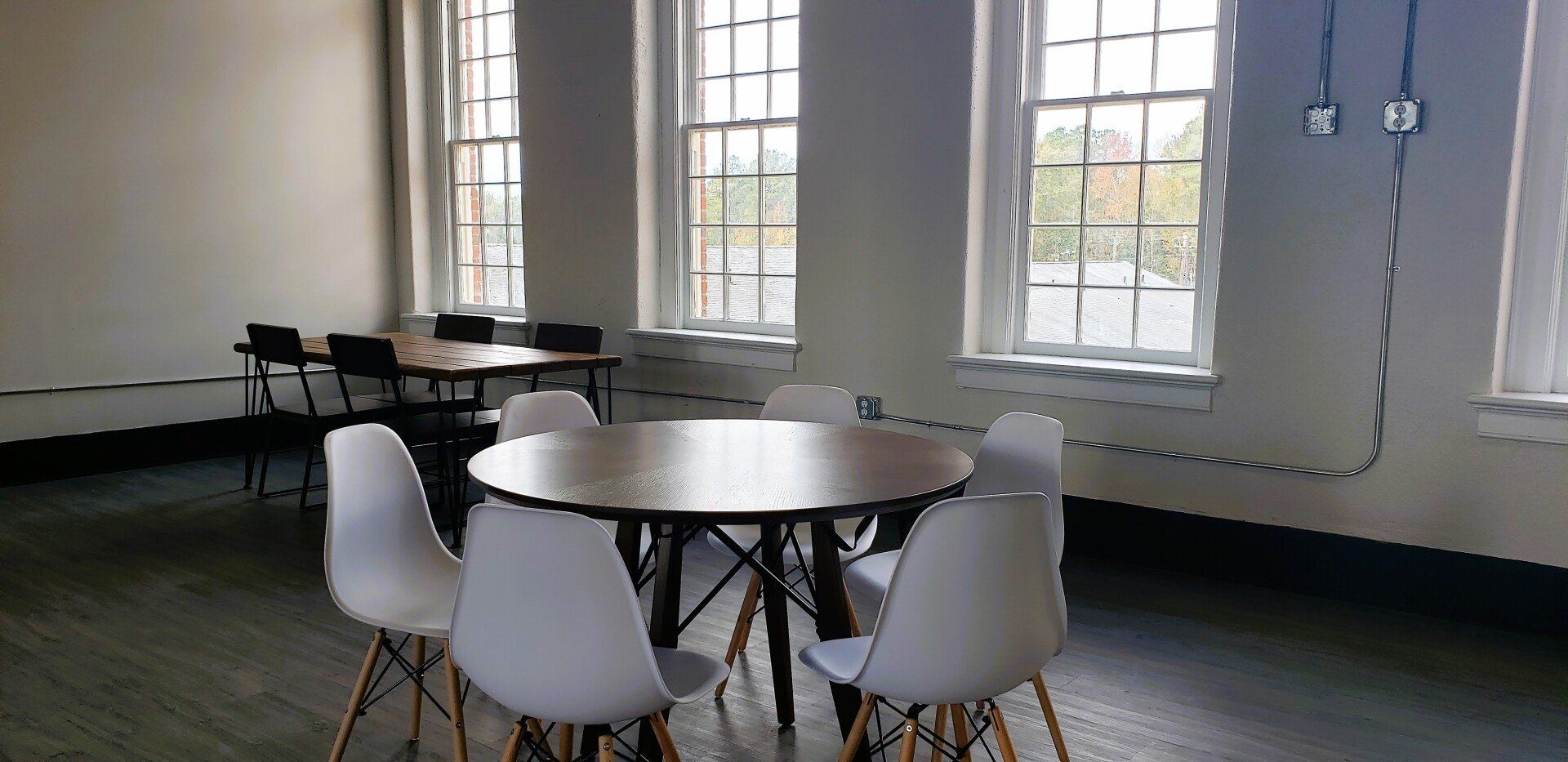 A room with a table and chairs in it and a lot of windows.